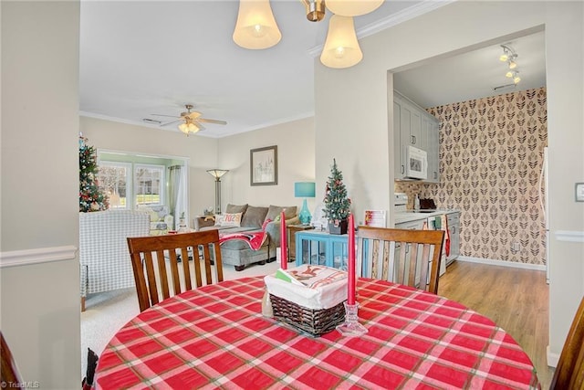 dining room with light hardwood / wood-style flooring, ceiling fan, and ornamental molding