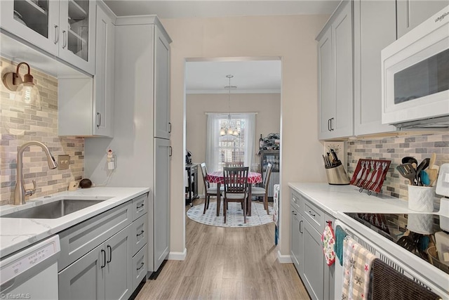 kitchen with light wood-type flooring, white appliances, tasteful backsplash, and sink