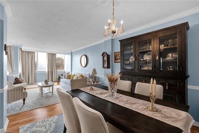 dining space with light wood-type flooring, crown molding, and a notable chandelier