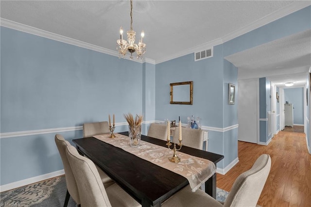 dining space featuring ornamental molding, light hardwood / wood-style flooring, and an inviting chandelier