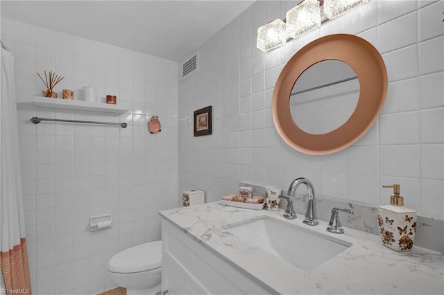 bathroom featuring tile walls, vanity, toilet, and backsplash