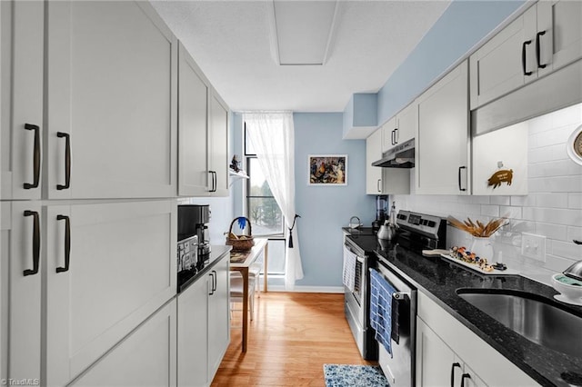 kitchen featuring white cabinets, appliances with stainless steel finishes, dark stone counters, and light hardwood / wood-style floors