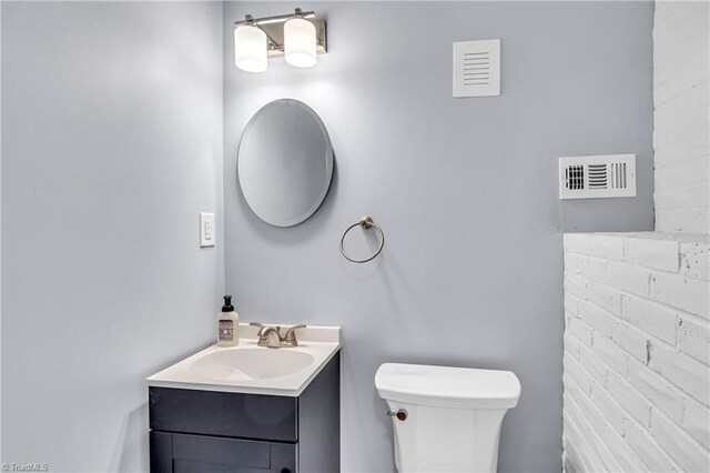 bathroom featuring visible vents, toilet, and vanity