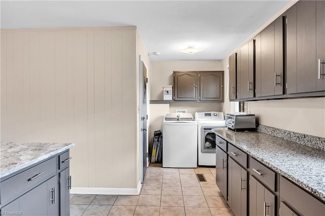 washroom featuring light tile patterned floors, cabinet space, washing machine and dryer, and a toaster