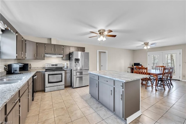 kitchen featuring a kitchen island, under cabinet range hood, light tile patterned flooring, stainless steel appliances, and a sink