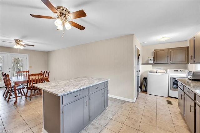 kitchen featuring a toaster, washing machine and dryer, light tile patterned floors, and a center island