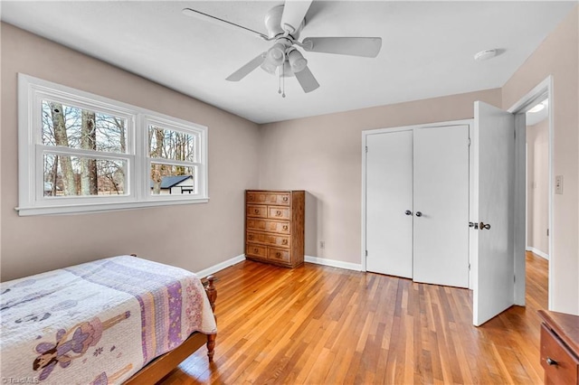 bedroom featuring baseboards, light wood-type flooring, a closet, and ceiling fan