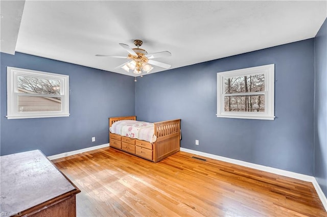 unfurnished bedroom with multiple windows, wood finished floors, visible vents, and baseboards