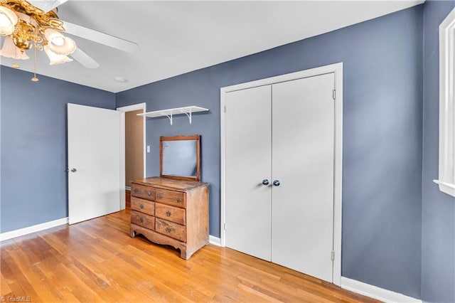 bedroom featuring light wood finished floors, ceiling fan, baseboards, and a closet