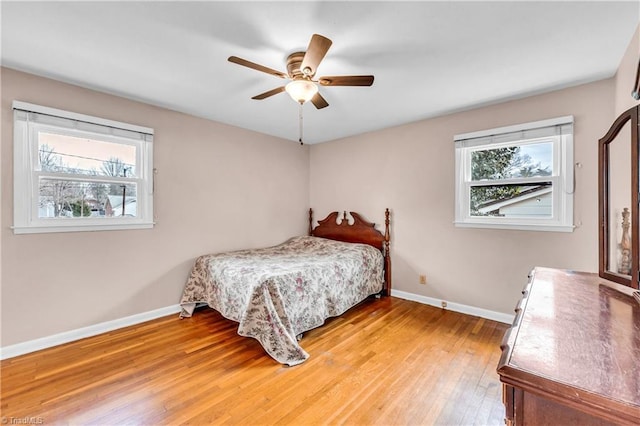 bedroom with multiple windows, baseboards, and light wood-type flooring