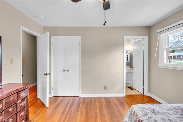 bedroom featuring a ceiling fan, baseboards, light wood-style flooring, a closet, and ensuite bathroom