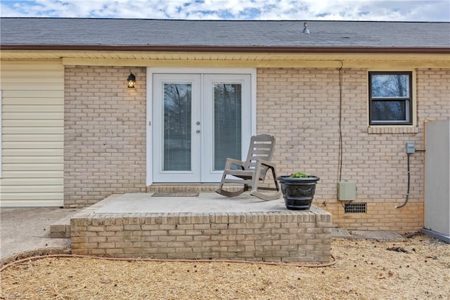 entrance to property featuring crawl space, a patio area, french doors, and brick siding