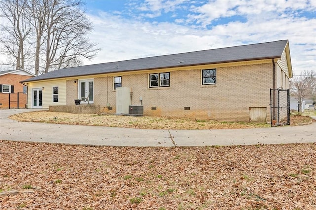 back of house with cooling unit, fence, french doors, crawl space, and brick siding