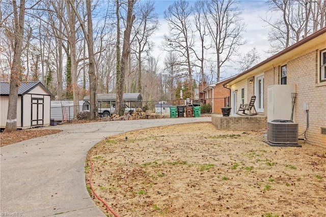 view of yard featuring central AC unit, a shed, fence, and an outbuilding