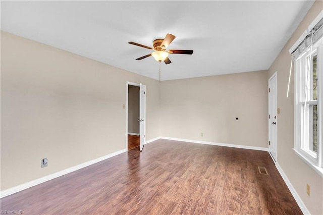 spare room featuring visible vents, baseboards, dark wood-style flooring, and ceiling fan