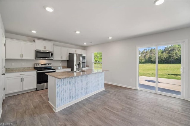 kitchen featuring a sink, stainless steel appliances, wood finished floors, an island with sink, and white cabinets