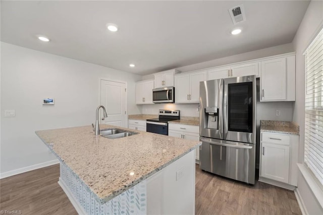 kitchen featuring a sink, stainless steel appliances, visible vents, an island with sink, and white cabinetry