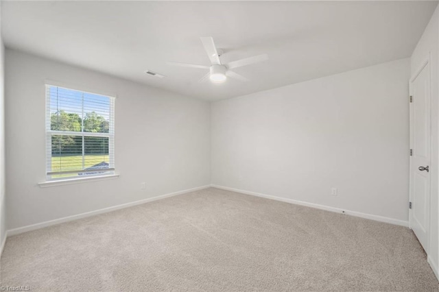 spare room with baseboards, ceiling fan, visible vents, and light colored carpet