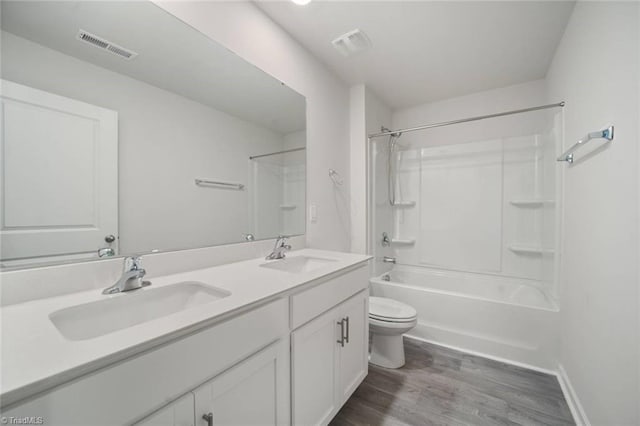 bathroom with toilet, visible vents, wood finished floors, and a sink