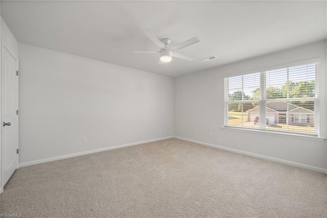 spare room with light carpet, baseboards, visible vents, and ceiling fan