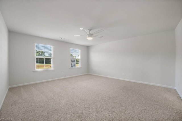 empty room with a ceiling fan, baseboards, and light colored carpet