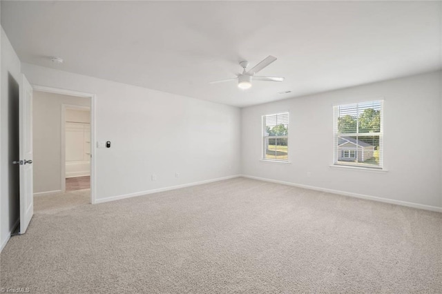 unfurnished room featuring light colored carpet, baseboards, and a ceiling fan