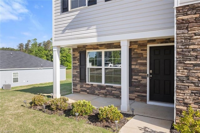 property entrance featuring central air condition unit, stone siding, and a lawn