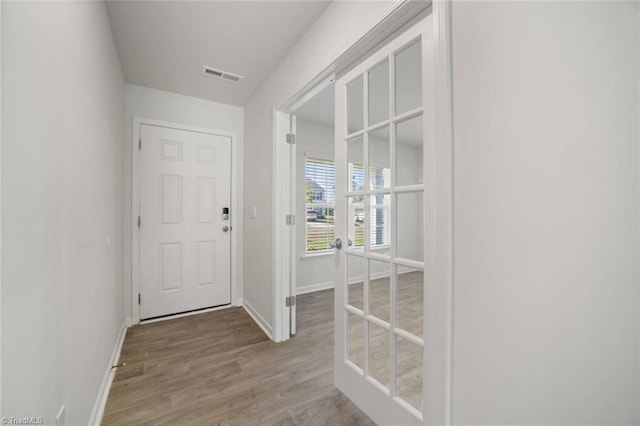 entryway with baseboards, visible vents, and wood finished floors