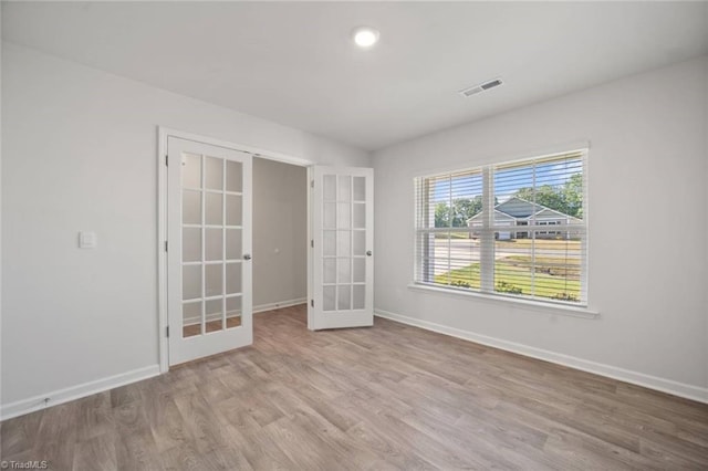 spare room with baseboards, french doors, visible vents, and wood finished floors