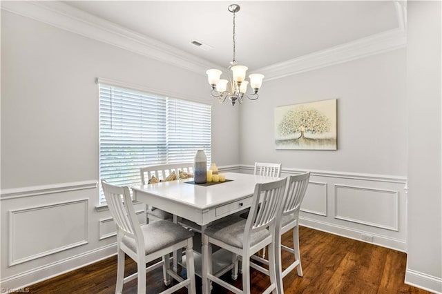 dining area with ornamental molding, dark wood-type flooring, and an inviting chandelier