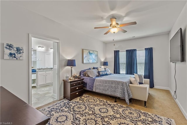 bedroom featuring light colored carpet, ensuite bath, and ceiling fan