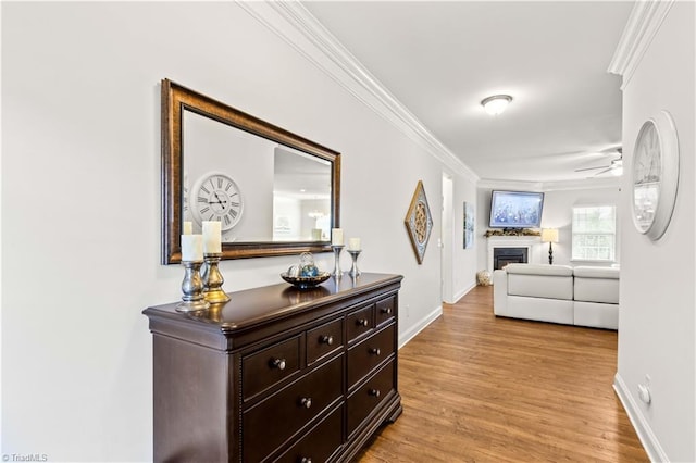 hallway with light wood-type flooring and ornamental molding