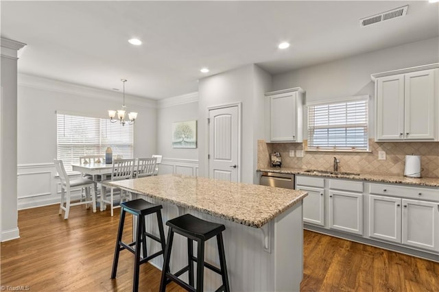 kitchen featuring backsplash, sink, decorative light fixtures, a kitchen island, and white cabinetry