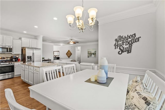 dining space with ceiling fan with notable chandelier, light hardwood / wood-style floors, and crown molding