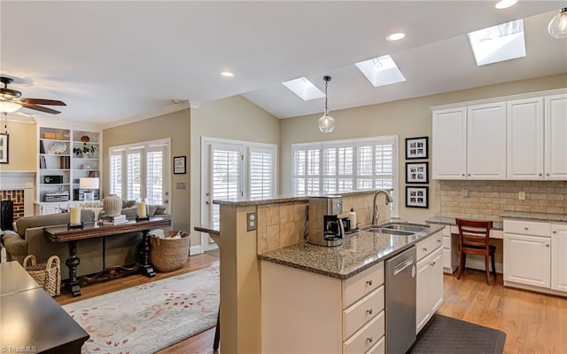 kitchen with a kitchen island with sink, a sink, white cabinets, light wood-style floors, and dishwasher