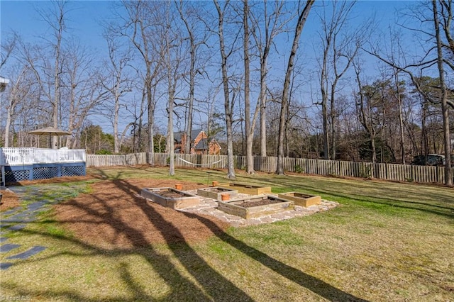 view of yard with a deck, a fenced backyard, and a vegetable garden