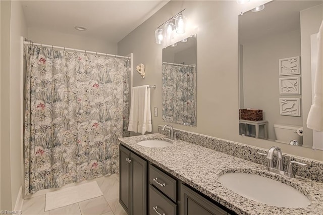 bathroom featuring toilet, double vanity, and a sink