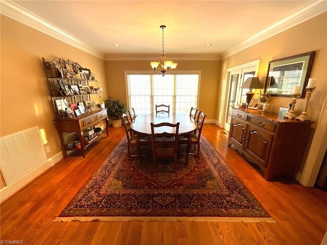 dining area with crown molding, a chandelier, and hardwood / wood-style flooring