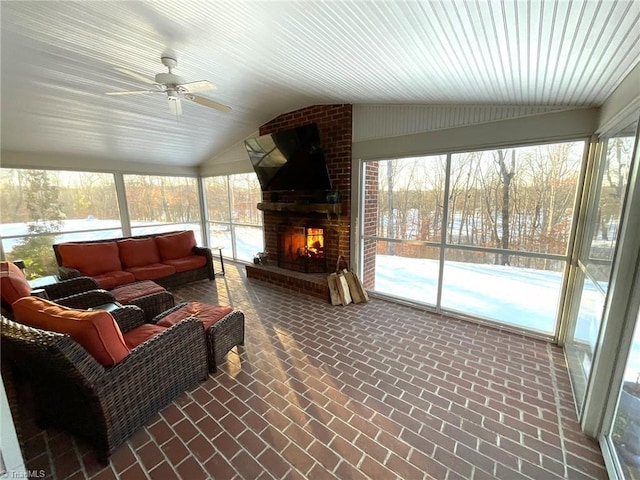 sunroom / solarium featuring ceiling fan, a fireplace, and vaulted ceiling