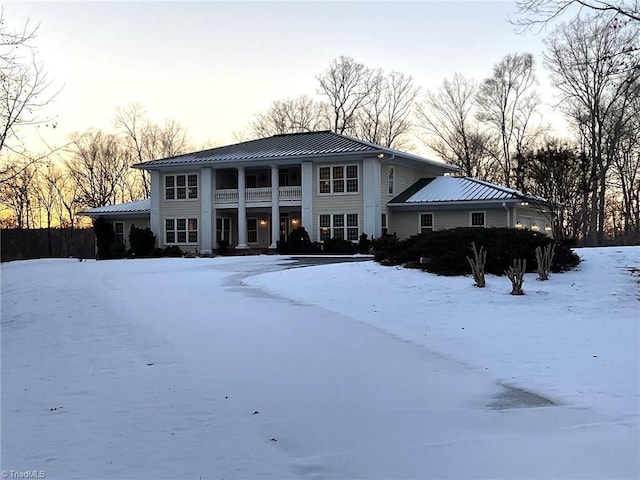 snow covered back of property featuring a balcony