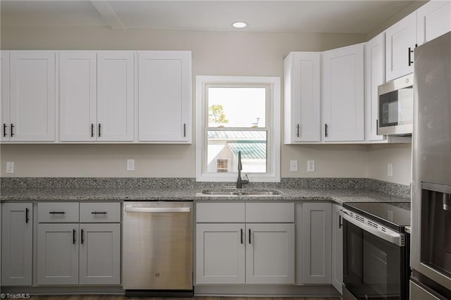 kitchen with white cabinetry, appliances with stainless steel finishes, sink, and light stone counters