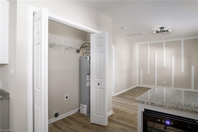 laundry area with wine cooler, hardwood / wood-style floors, gas water heater, and hookup for an electric dryer