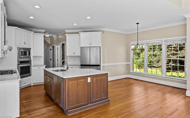 920 James Doak Pkwy, Greensboro, NC 27455 - kitchen featuring stainless steel appliances, crown molding, light countertops, backsplash, and a center island with sink