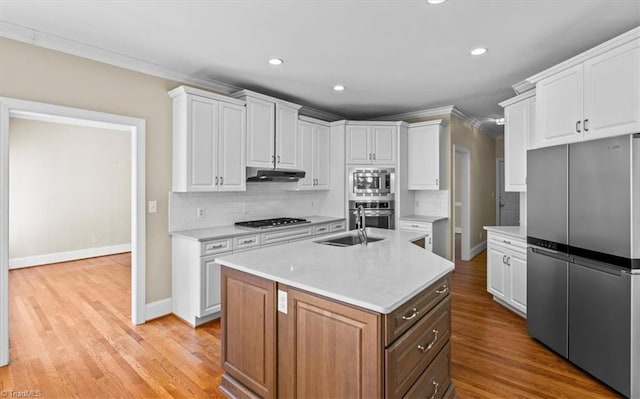920 James Doak Pkwy, Greensboro, NC 27455 - kitchen with stainless steel appliances, under cabinet range hood, crown molding, white cabinets, and tasteful backsplash