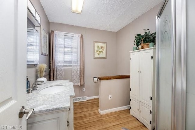 bathroom with hardwood / wood-style floors, vanity, and a textured ceiling