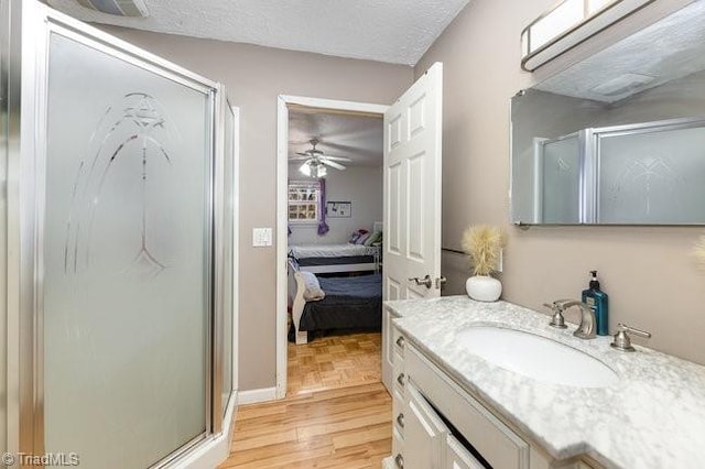 bathroom featuring vanity, a textured ceiling, a shower with door, ceiling fan, and wood-type flooring