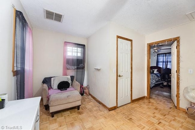 living area with ceiling fan, a textured ceiling, and light parquet floors