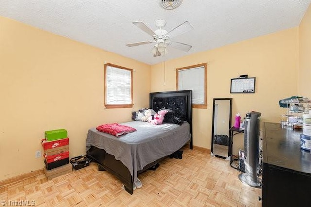 bedroom featuring ceiling fan, a textured ceiling, and light parquet flooring