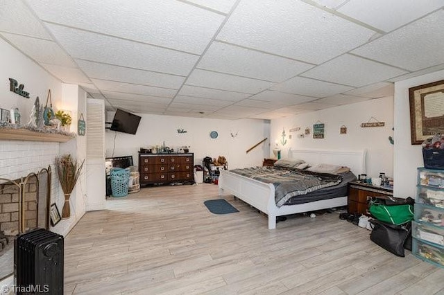 bedroom with a drop ceiling and light hardwood / wood-style flooring