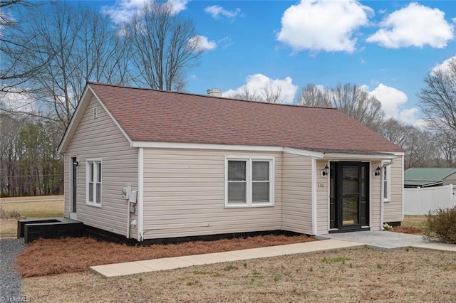 view of front of property with a front yard, fence, and a shingled roof